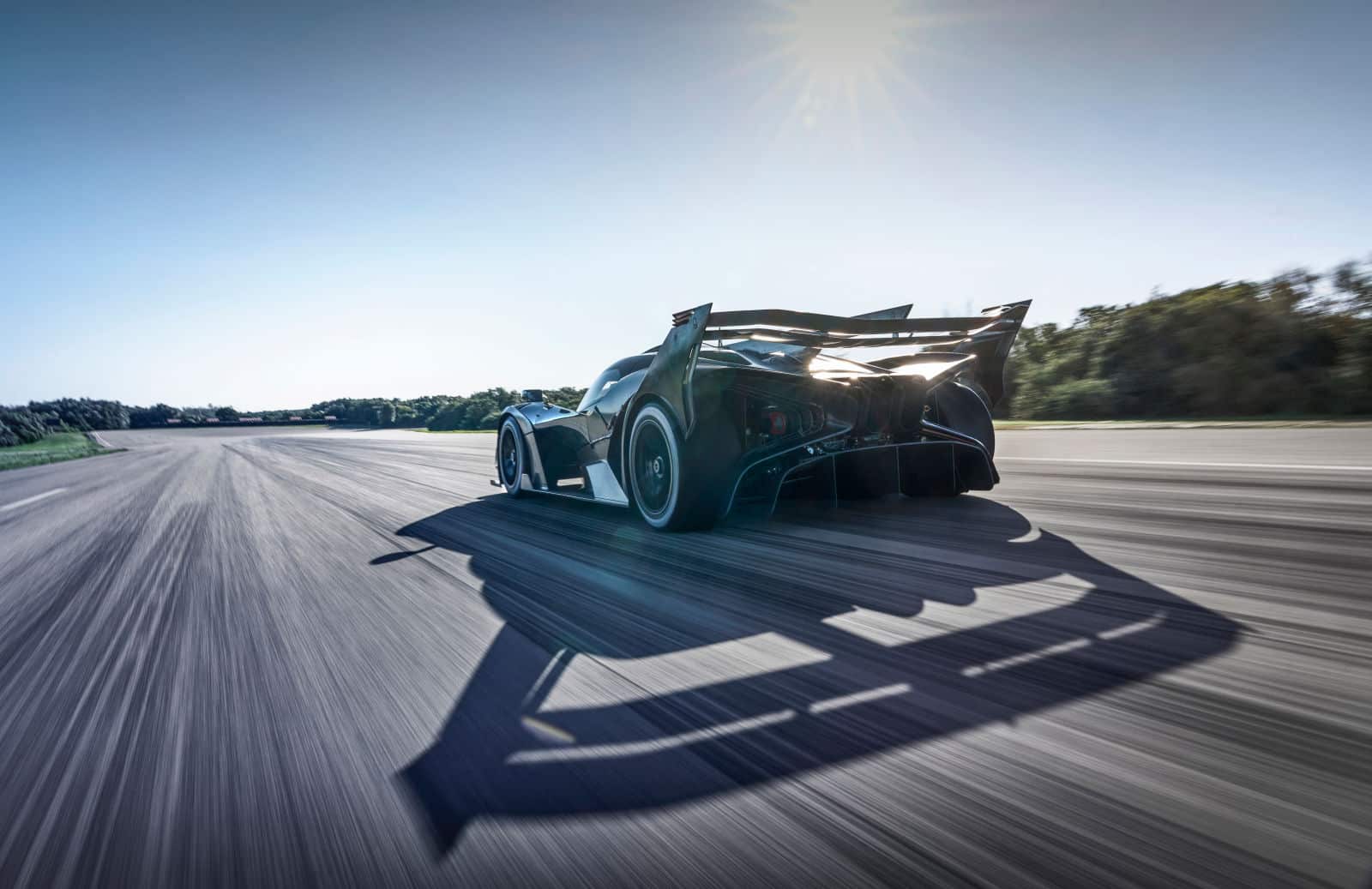 Ein Bugatti Bolide beschleunigt auf einer sonnendurchfluteten Rennstrecke, mit dem Sonnenlicht, das die aerodynamischen Kurven und den kräftigen Abtrieb des Fahrzeugs hervorhebt.